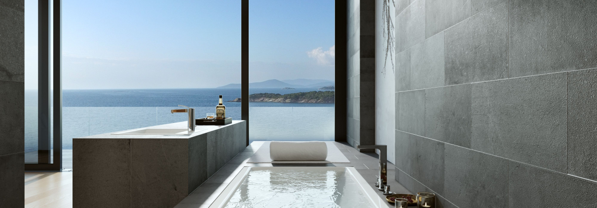 Baño de hotel con bañera y lavabo junto a ventanal con vista al mar