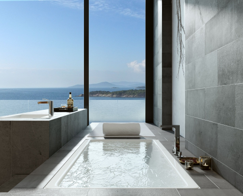 Baño de hotel con bañera y lavabo junto a ventanal con vista al mar